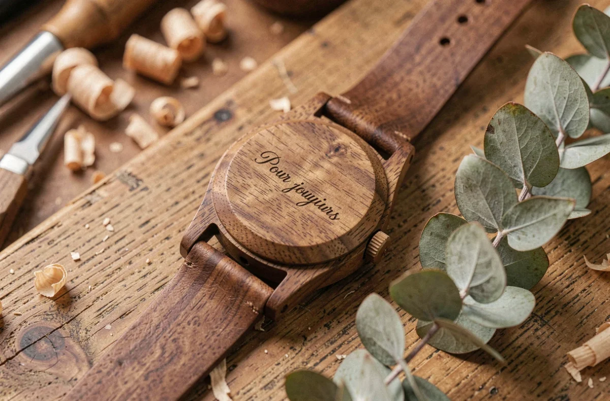 Montre en bois avec message gravé 'Pour toujours' posée sur une table en chêne rustique dans un atelier artisanal